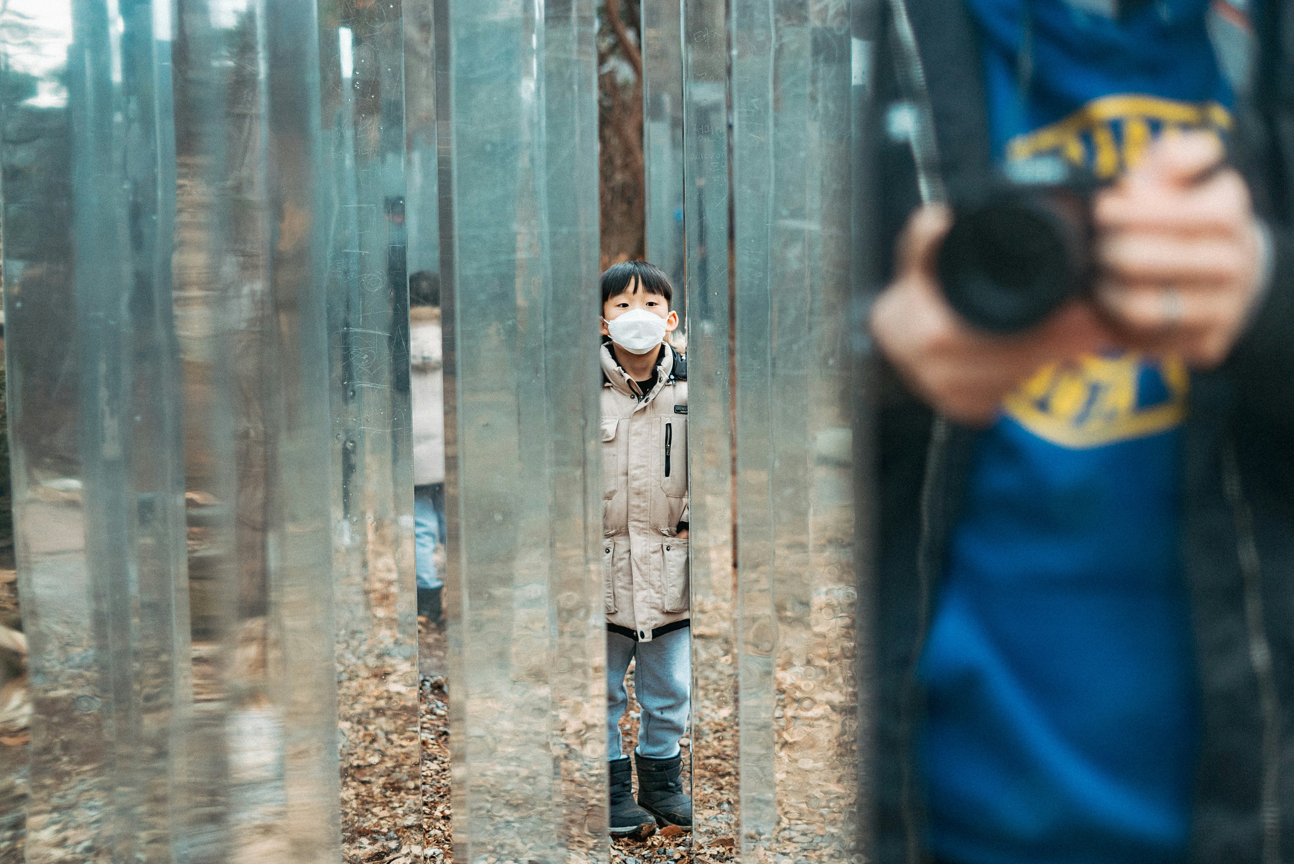 boy in blue shirt and gray pants standing beside wooden wall